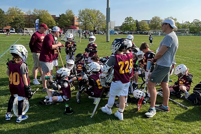 Lacrosse team taking a knee with coaches.